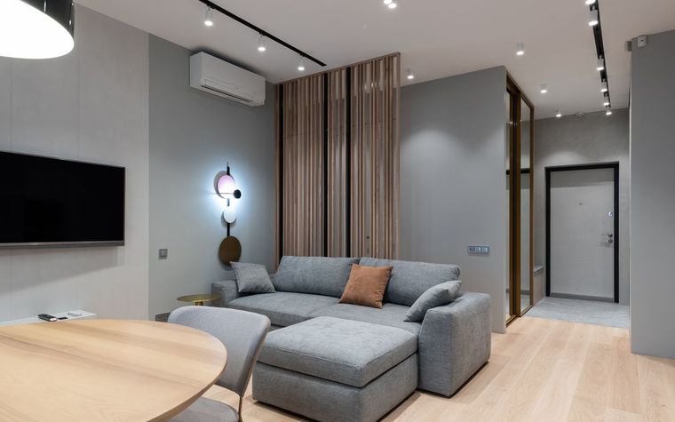 Modernes Wohnzimmer mit Sofa und Essplatz, an der Wand ein Klima-Innenger&auml;t.